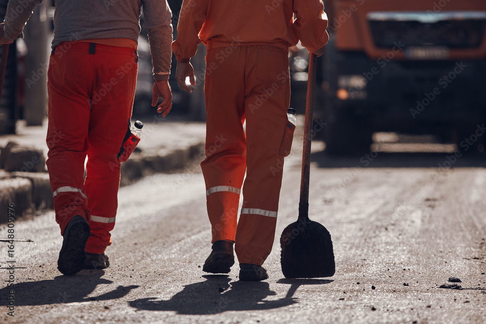 Fototapeta premium Construction workers working on a new asphalt layer on a public street.