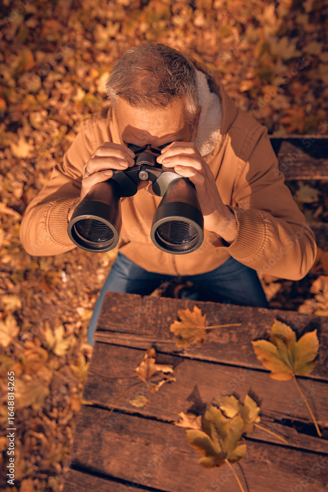 Fototapeta premium Amateur birdwatcher observing birds and other animals in nature with binoculars.