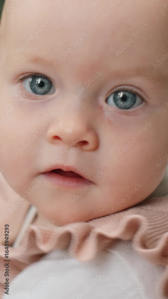 Vertical close-up portrait of Caucasian one-year-old baby girl with grey eyes looking at camera in childrens clinic Vertical close-up portrait of Caucasian one-year-old baby girl with grey eyes looking at camera in childrens clinic