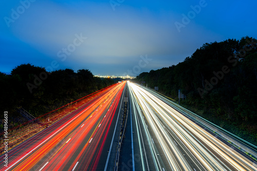 Light trails illuminating highway at dusk with city lights in background