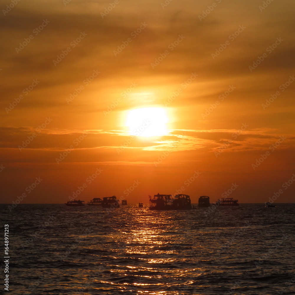 Obraz premium bright red sunset with shadows of boats in the water
