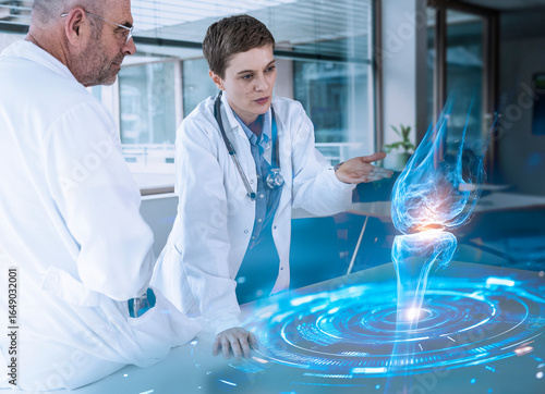 Doctors analyzing holographic knee anatomy in medical consultation
