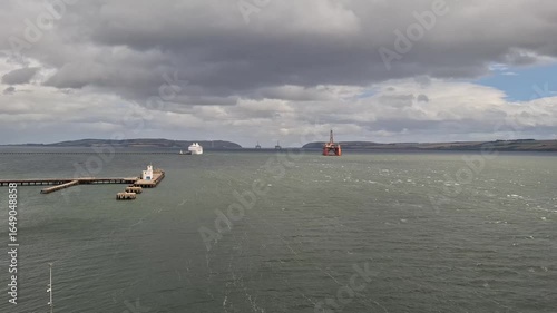 invergordon unitrd kingdom aug 9 2024 Dramatic Seascape with Pier, Ship, and Platforms Under Moody Skies