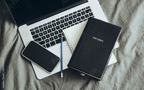 Bible, phone, laptop and cup of coffee on a grey bed background. studying Bible.