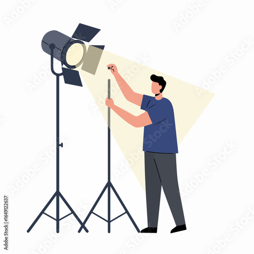 Male professional adjusting a large spotlight on a tripod, illuminating a scene for a photoshoot or film production, showing lighting setup.