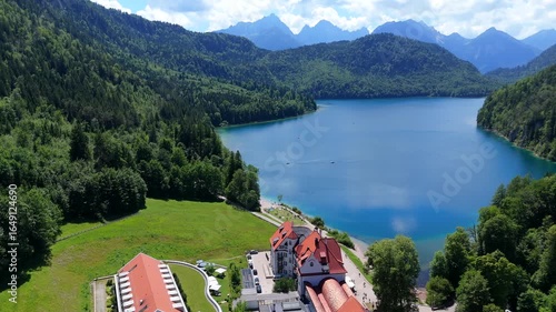 Turquoise Alpsee Lake in Bavaria Germany surrounded by lush green forest and mountain peaks under a bright summer sky