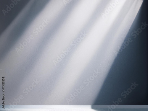 A minimalist, grayscale scene with a table or platform. Diagonal streaks of sunlight and shadow are cast across the surface and wall.