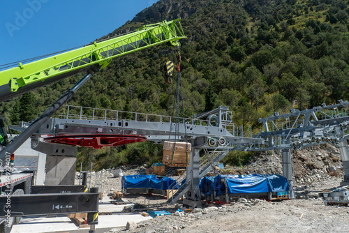 Foto Worksite showing aerial lift, Aerial cableway station assembly mobile crane lifting crate to terminal