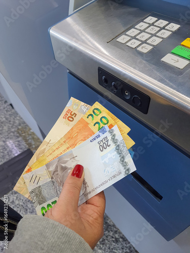 Real money bills in the hands of a woman at an ATM