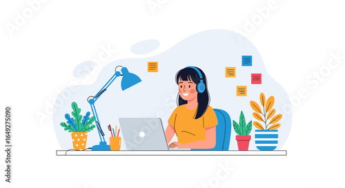 Young woman with headphones happily working on a laptop at a desk with plants and a lamp, illustrating remote work or online learning.