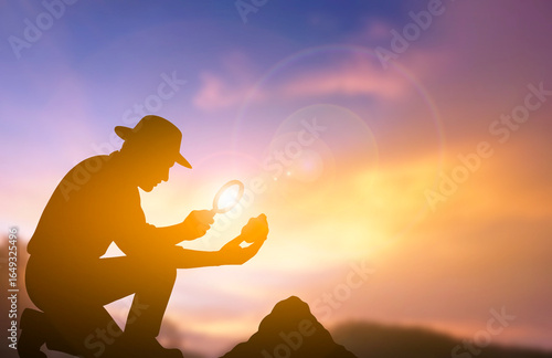 Gold prospector examining rock with magnifying glass silhouette