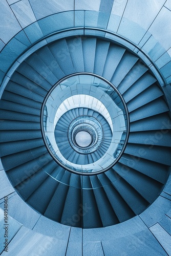 An aerial shot of a spiral staircase in a modern building, looking straight down to create a hypnotic geometric pattern.