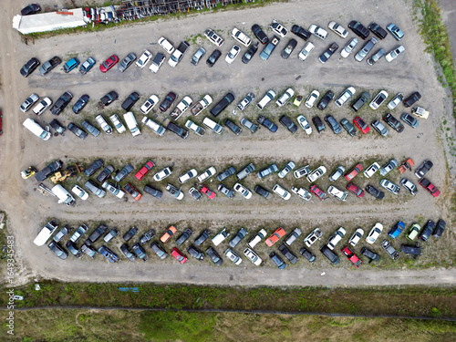 Quadro em tela Drone aerial view image of a vehicle scrap yard showing rows of damaged and end-of-life cars, trucks, and vans arranged diagonally on unpaved dirt lanes for dismantling and recycling