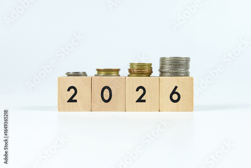 Wooden blocks showing year 2026 with stacked coins symbolizing financial growth and savings planning for the future.
