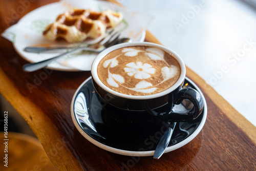 Hot coffee latte with latte art milk foam in cup mug and Homemade Belgian Waffles with honey on wood desk on top view. As breakfast In a coffee shop at the cafe,during business work.