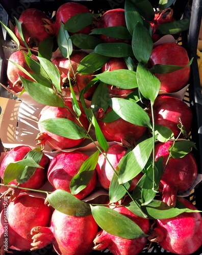 Ripe pomegranates with green leaves in a box,view from above.