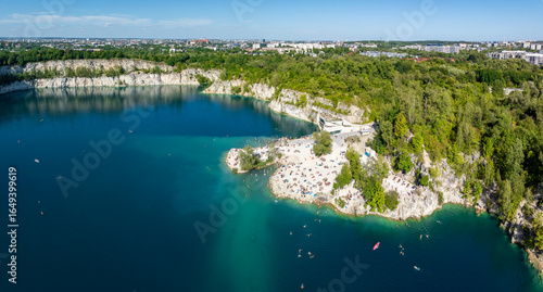 Zakrzówek, Krakow, Poland. Beach, swimming and paddling area. Zakrzowek lake with steep cliffs of flooded limestone quarry. Public recreational place. Aerial panorama. City center in the background