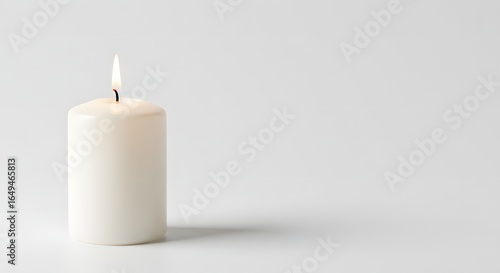 Wallpaper Mural A single, lit white candle casting a soft shadow against a plain, light background. Torontodigital.ca