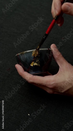 kintsugi gold cracks restoration process, Japanese black bowl fixed with the antique kintsukuroi restoration technique, the beauty of imperfections, representation of a trauma