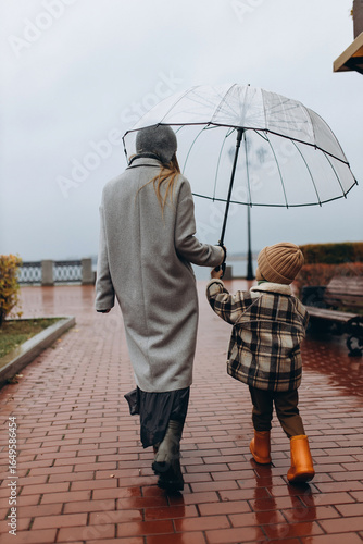 mother and little son in the park on a rainy autumn day, view from the back
