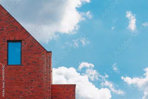 Papier peint Red brick building with gable and window against blue sky, copy space