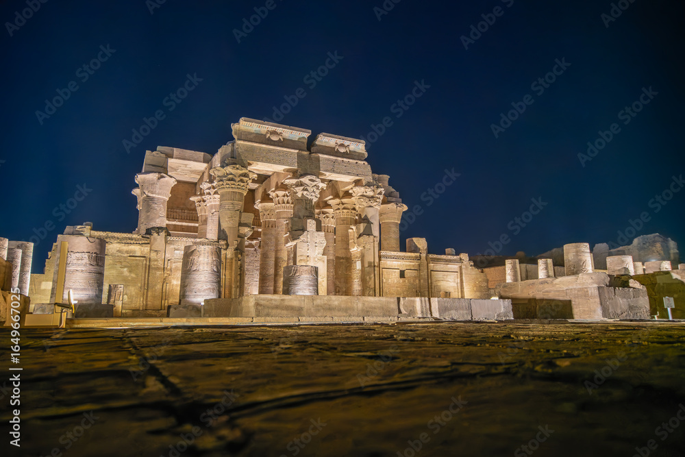 Fototapeta premium The magnificent Temple of Kom Ombo is illuminated at night against a dark sky, highlighting its ancient columns and powerful structure.