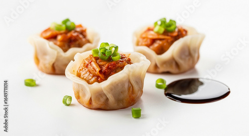 Three delicious dim sum dumplings filled with savory meat and topped with fresh green onions, served with a side of soy sauce.