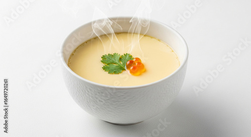 A delicate white bowl of hot, steaming Japanese savory egg custard, Chawanmushi, topped with a sprig of cilantro and salmon roe.