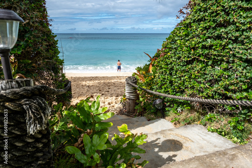 Pathway to sandy beach with fisherman at Kahana Bay, Oahu, Hawaii on January 28, 2023