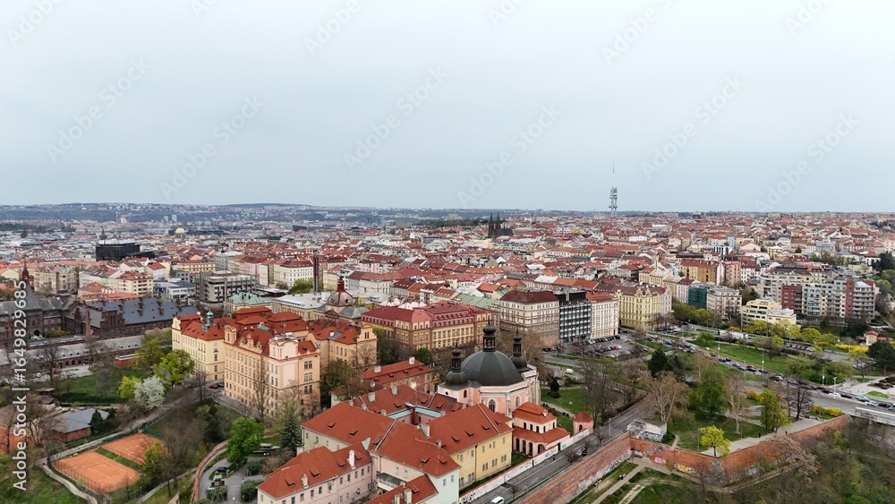 Fototapeta premium Aerial panorama of a historic European city with endless red rooftops, domed churches, and a modern tower rising above. Contrast of heritage architecture and urban development in one frame.
