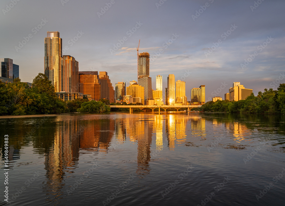 Fototapeta premium Tallest building in Texas over Lady Bird Lake in the city skyline of Austin TX in summer 2025 as the sun casts a golden light