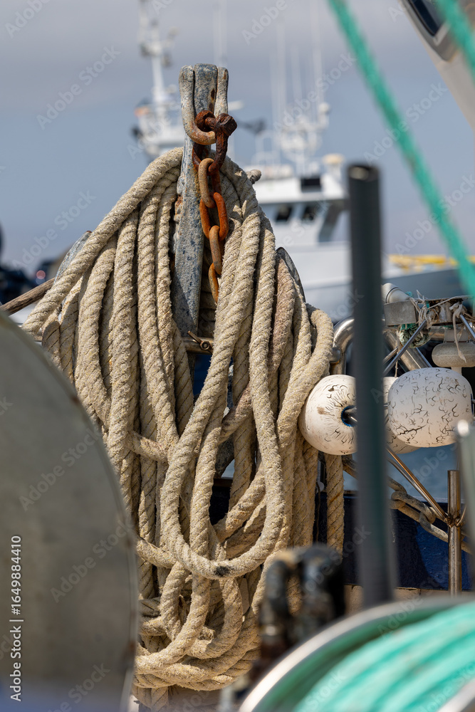 Obraz premium Rusty anchor chain holding fishing rope on a boat