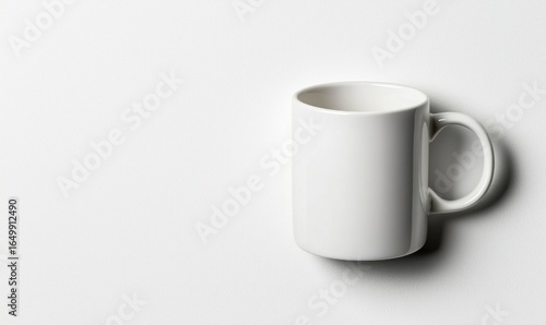 White ceramic mug angled to the right against a blank white surface. Simple, minimalist, and bright