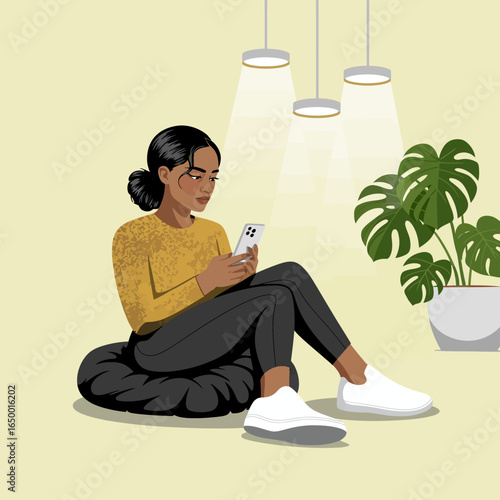 A young woman sits comfortably on a black cushion, engaged with her smartphone, surrounded by soothing lighting and a vibrant plant, creating a tranquil atmosphere.