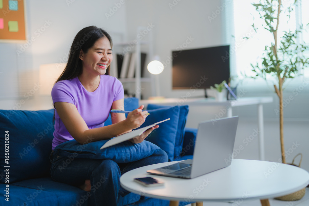 Naklejka premium Young Asian Woman Taking Notes While Studying Online From Home