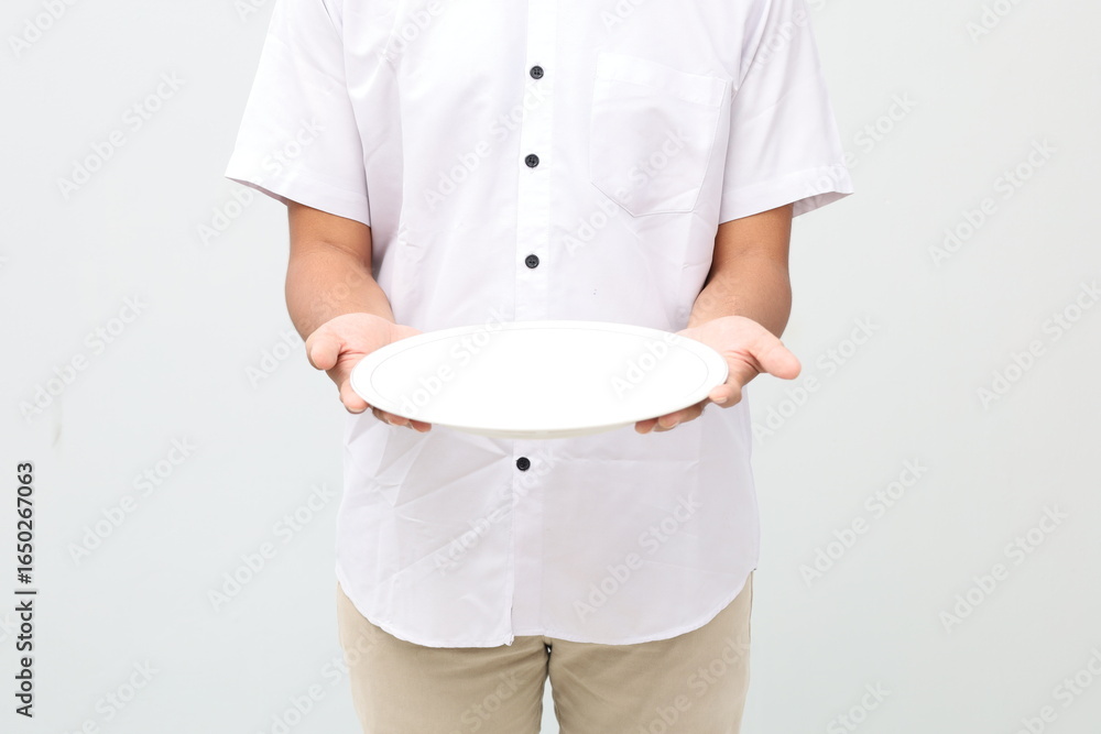 Asian muslim man standing while holding an empty plate Asian muslim man standing while holding an empty plate