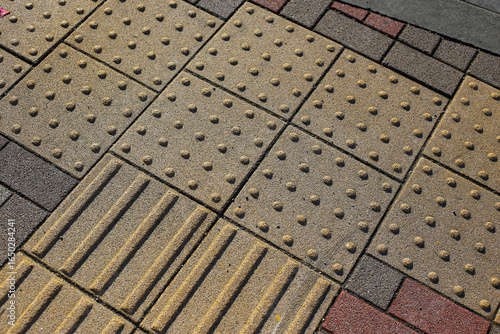 Valokuva Yellow tactile paving guiding path for visually impaired people on a city sidewalk and street crossing