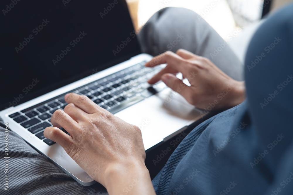 Fototapeta premium Close up, woman hands typing on laptop computer at home. Young woman sitting on the floor, put laptop on herlap, remote working form home, business casual, digital nomad lifestyle