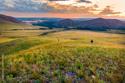 tourists walk along the ridge of karamuruntau against the backdrop of andreevskie cones in the evening at sunset