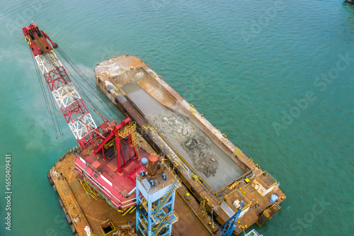 Slika na platnu Aerial shot of dredging barge transferring rocks and slurry onto transport barge during marine construction work
