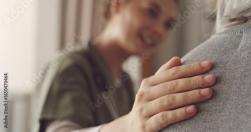 Healthcare worker touching elderly patient's shoulder with compassion and talking