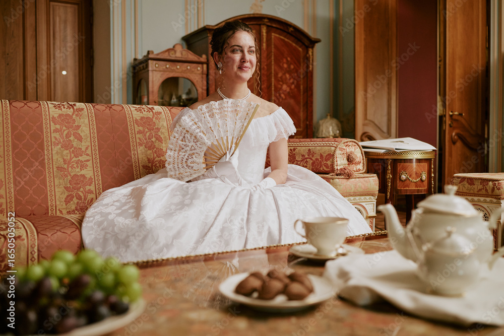Ταπετσαρία Caucasian young adult woman sitting on ornate sofa holding lace fan wearing hist
