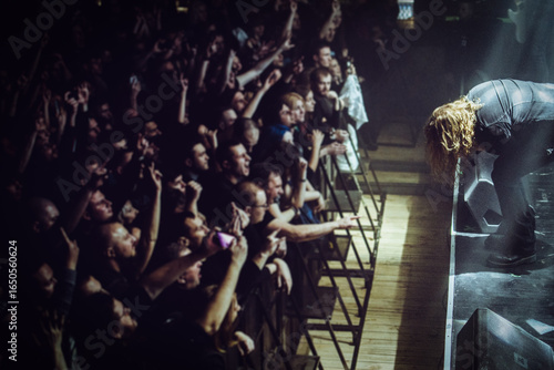 Metal vocalist performing with passion on stage during a club show, with colorful dramatic lighting