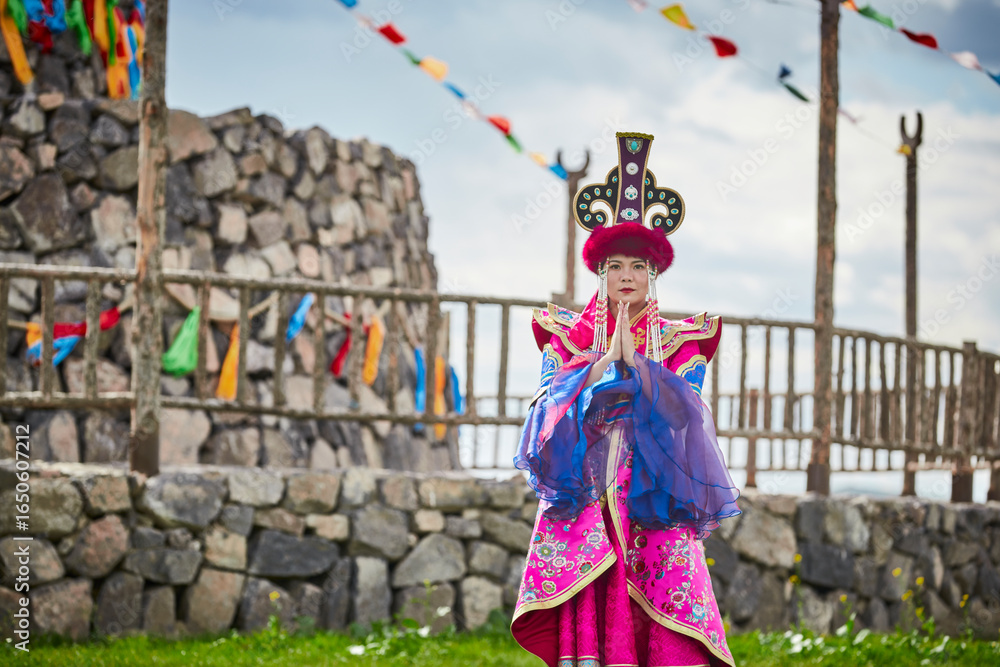 Naklejka premium Mongolian girls dressed in luxurious Mongolian costumes in front of an obo on the grassland