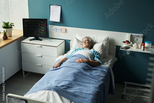 Photos Senior Caucasian woman lying in hospital bed with medical monitor displaying vit
