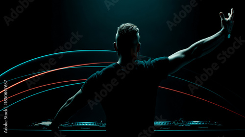 Silhouette of male DJ in black t-shirt facing crowd, arm raised, colorful arcs of cyan and red lights above booth, dark concert setting