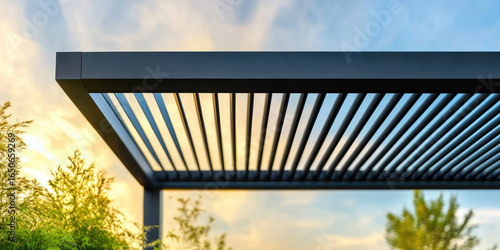 A modern slatted pergola is shown against a vibrant sunset sky with surrounding greenery. Outdoor architecture and nature harmony