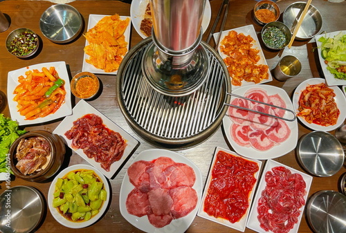 Traditional Korean BBQ Setup with Various Meats, Vegetables, and Side Dishes