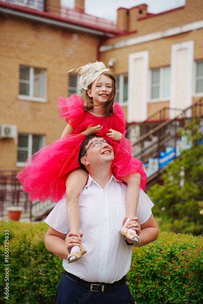 Fototapeta premium Happy well-dressed family on a walk. Dad and little daughter 