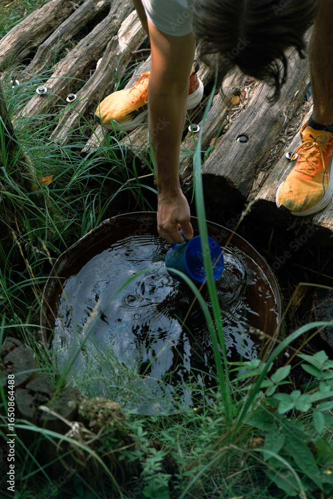 Obraz premium A person drawing water from a spring